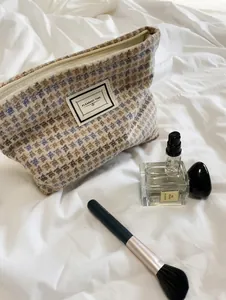 Close-up of khaki and blue houndstooth tweed cosmetic bag with Pleasant Time fabric label