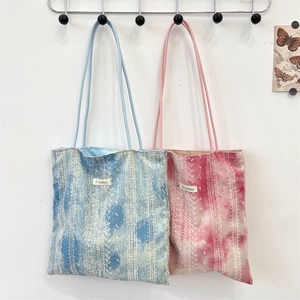 Detail of blue and pink tie-dye lace tote bags with sorakka labels on wall hooks