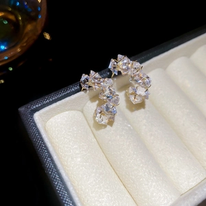 Macro shot of gold C-shaped earrings with multi-faceted crystals in a jewelry box