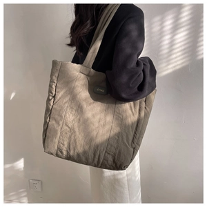 Olive brown nylon tote bag showing carrying effect on shoulder with soft natural lighting