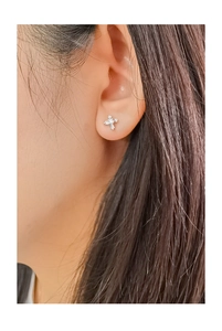Close-up of a minimalist silver cross stud earring with sparkling zircons on a model