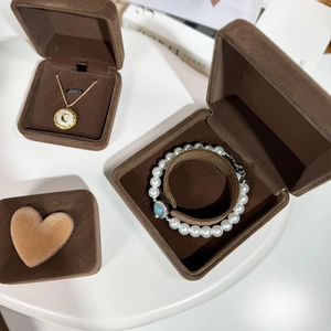 Brown velvet jewelry storage box featuring pearl bracelets and moon pendant necklaces