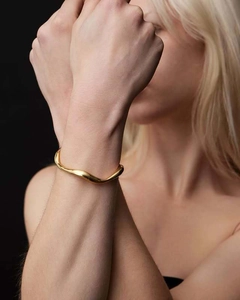 Close-up of a wavy 18K gold plated irregular stainless steel bracelet on a wrist