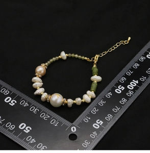 Green bead and natural pearl bracelet size measurement with scale on black background