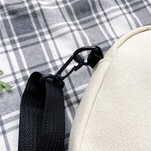 Detailed macro view of the black nylon strap and clip hook on the off-white canvas bag