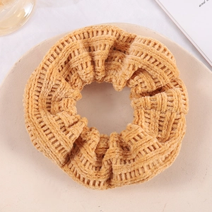 Orange-brown chunky waffle knit scrunchie displayed on a beige plate for hair styling