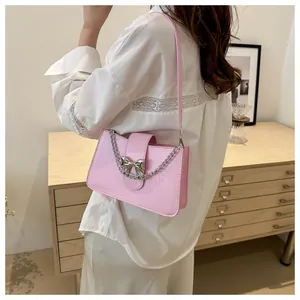 Detail of pink shoulder bag with silver bow and metallic chain on a female model