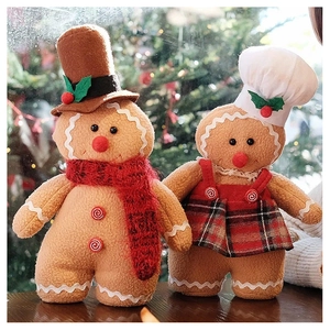 Close-up of plush gingerbread couple with chef hat and scarf against a Christmas tree