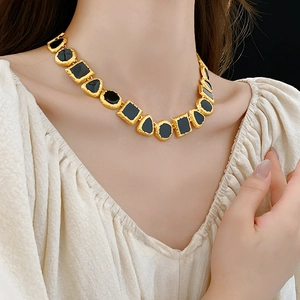 Close-up of a vintage golden necklace with black geometric drip oil stone inlays on a model