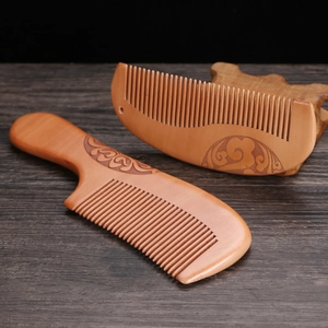 Natural peach wood comb set with elegant carved patterns on a dark wooden surface