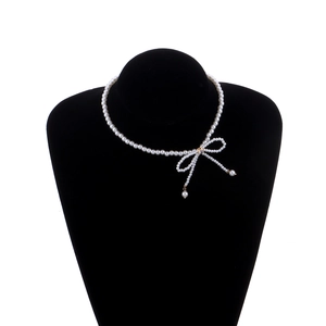Elegant pearl choker necklace featuring a bow pendant on a black velvet neck bust display
