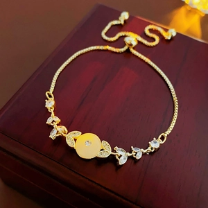 Dettaglio del bracciale dorato regolabile con pietra gialla e zirconi su legno