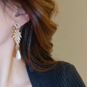 Detail of leaf-shaped rhinestone drop earrings with waterdrop pearl on model