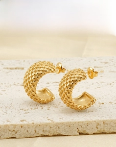 Gros plan de boucles d'oreilles créoles dorées en C avec motif grillagé à pois