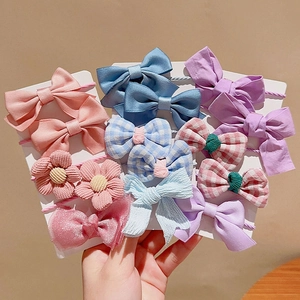 Detailed view of handmade bow and flower hair ties in pastel pink and blue on cards