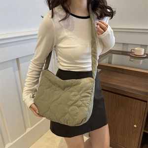 Chic olive green quilted tote bag with heart pattern worn in a cafe setting