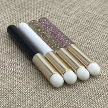 Detail of round head lip and concealer brushes with gold ferrules on beige fabric