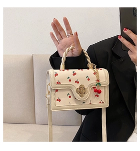 Detail of white cherry print handbag with golden flower clasp and neat edge stitching