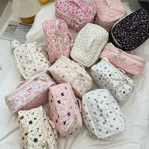 Flat lay of quilted cosmetic bags with floral, bear, and cherry patterns and top handle