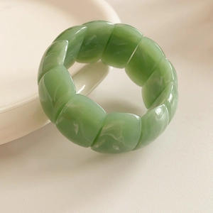 Detail of light green acrylic stretch bracelet with marbled texture and rectangular beads