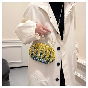 Chic pumpkin evening bag with green stones and gold handle worn on a beige trench coat