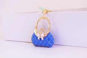 Macro shot of blue handbag charm with sparkling rhinestones and white bow detail