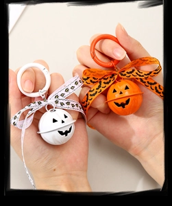 Close-up of cute Halloween pumpkin bells with bat-patterned ribbons held in hand