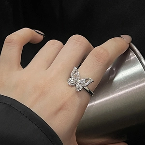 Macro shot of silver butterfly ring set with sparkling zircons on finger