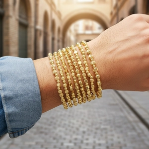 Macro view of multi-layer gold beaded bracelets with textured geometric beads
