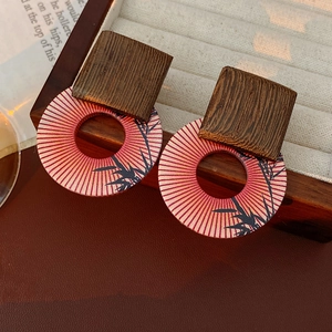 Macro shot of geometric wooden earrings with red bamboo prints and natural textures
