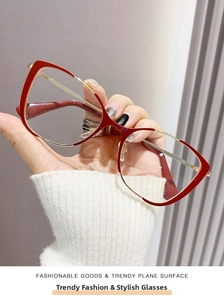 Detail of red and gold oversized cat-eye metal glasses frame held by hand for style