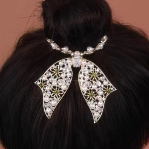 Detail of silver bow hair clip with white pearls and green rhinestone floral accents