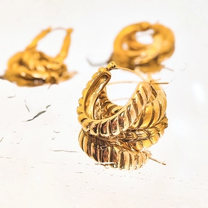 Macro detail of gold-plated stainless steel twisted hoop earrings with water drops reflection