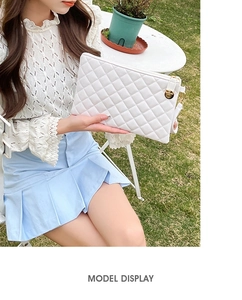 Outdoor model display of white quilted handbag with golden metal hardware lock