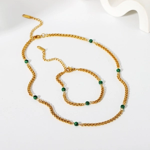 Ensemble collier et bracelet en malachite dorée avec chaîne torsadée sur fond blanc