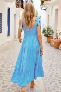 Detail of blue backless tiered dress with polka dot texture and tie-up bow shoulder straps
