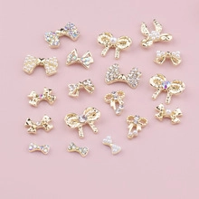 Detailed view of assorted golden bow nail charms with pearls and sparkling rhinestones