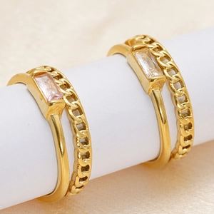 Macro detail of gold double-layer chain rings featuring rectangular pink gemstones