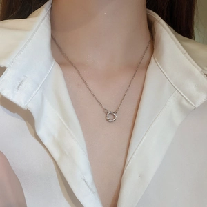 Close-up of a silver zircon circle pendant necklace on a model wearing a cream shirt