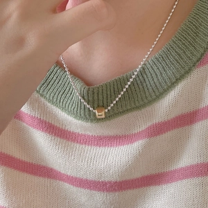 Close-up of minimalist 925 silver beaded necklace with gold cylindrical pendant