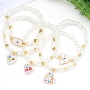 Detail of three-piece pearl bracelet set with enamel evil eye and floral heart charms