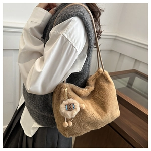 Detail view of brown plush tote bag with lamb pendant and soft faux fur texture