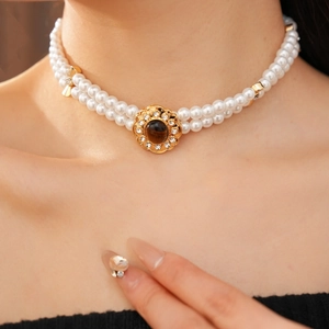 Dettaglio della collana di perle a due fili con fiore dorato e pietra occhio di tigre