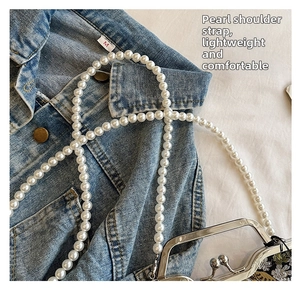 Detailed shot of white faux pearl shoulder strap with elegant silver metal clasp