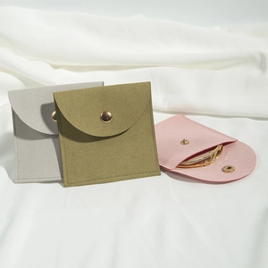 Macro detail of microfiber jewelry pouches with gold snap buttons in grey green and pink