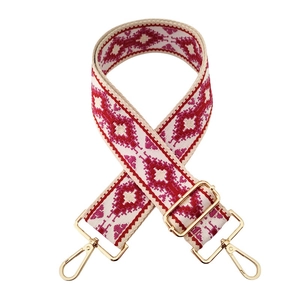 Close-up of ethnic geometric jacquard bag strap with gold metal hooks and red pink weave