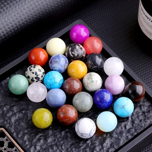 Macro shot of 24 colorful polished 16mm natural crystal balls on a black textured tray
