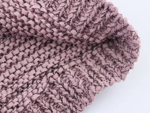 Close-up of pink knit fabric showing detailed crochet texture and thick yarn quality