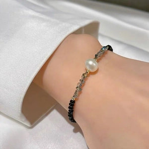 Elegant beaded bracelet with white pearl, black beads and grey faceted crystals on wrist