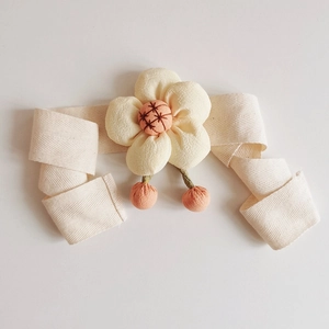 Detail of fabric flower curtain tieback with beige bow and pink plush pom-pom charms